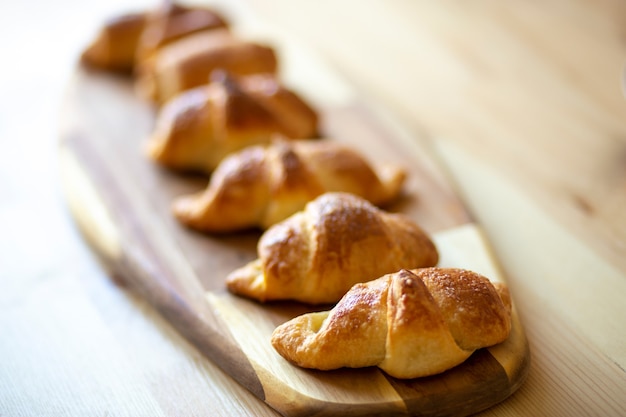 Foto croissant, zelfgemaakte vers gebakken goederen liggen op een prachtig bamboebord op een houten tafel