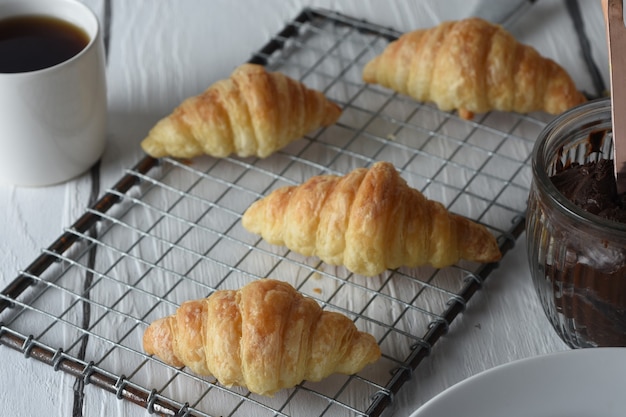 croissantFreshly baked croissants on a tray with a small jar of jam for breakfast