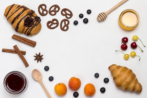 Croissants and figured cookies, berries, apricots honey, jam, cinnamon. Set of products for nutritious breakfast.