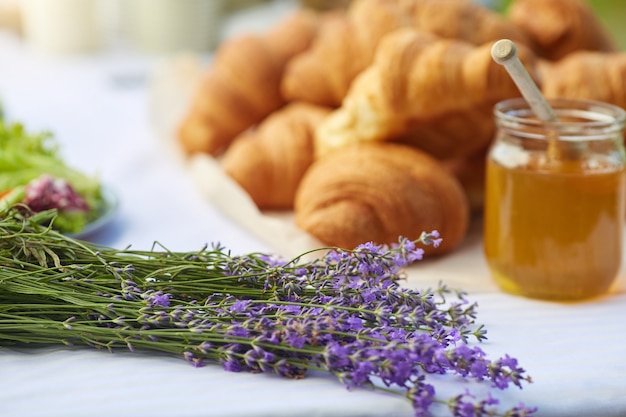 Croissants and honey on table in lavender field