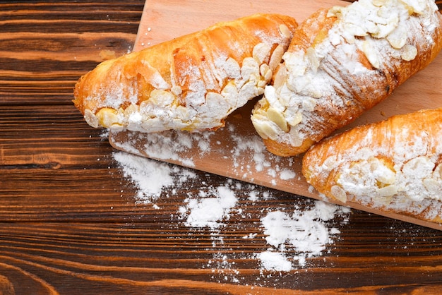 Croissants met amandelen en thee op een houten tafel.