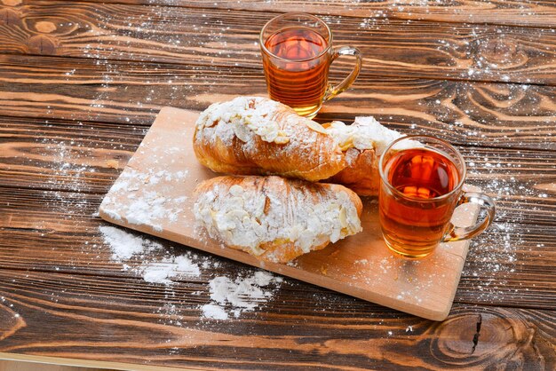 Croissants met amandelen en thee op een houten tafel