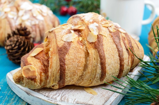 Croissants met amandelvlokken, koffiemok op een blauwe houten achtergrond. Ontbijt. Traditionele Franse gebakjes.