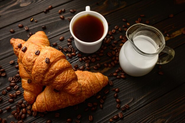 Foto croissants met koffie en koffiebonen op een houten ondergrond