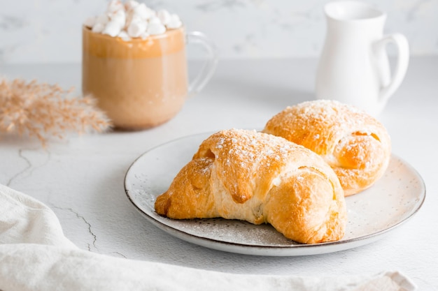 Croissants op een bord en heerlijke koffie met marshmallows in een kopje op tafel lifestyle zelfgemaakte snack close-up