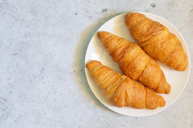 Foto croissants op witte plaat op lichte betonnen achtergrond bovenaanzicht met kopieerruimte