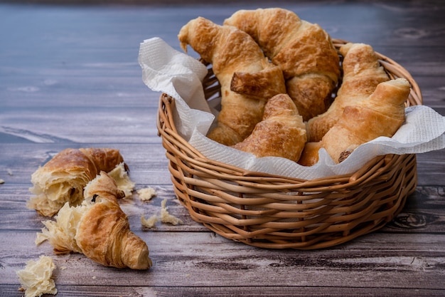 Croissants in a pan or bread basket and Croissants parts and crumbs on the table.