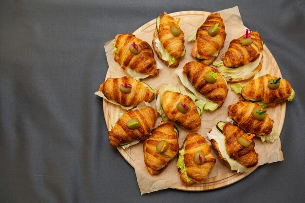 Croissants sandwiches with fish on a round wooden board.