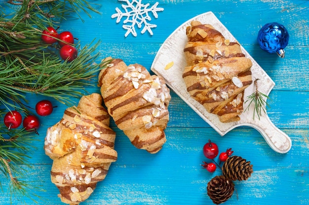 Croissants with almond flakes on a blue wooden background. Breakfast. Traditional French pastries.