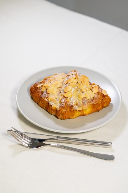 Croissants with almonds and powdered sugar are served on a plate