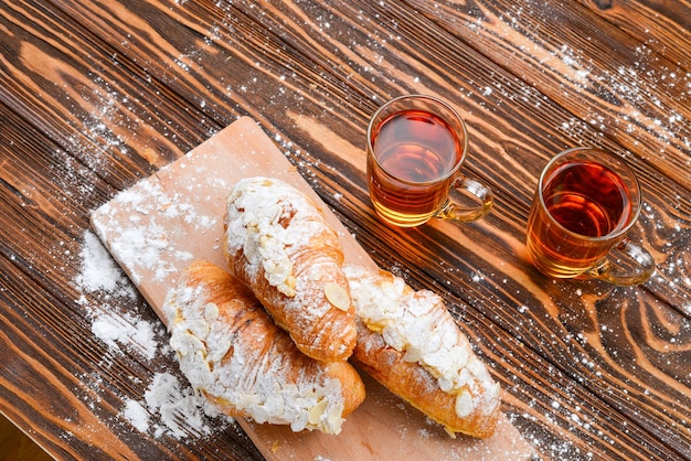 Cornetti con mandorle e tè su un tavolo di legno.