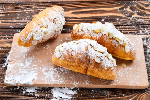 Croissants with almonds and tea on a wooden table.