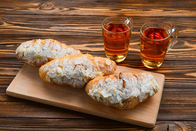 Croissants with almonds and tea on a wooden table