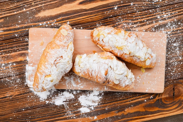 Croissants with almonds and tea on a wooden table