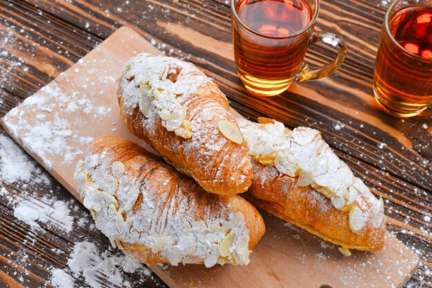 Croissants with almonds and tea on a wooden table