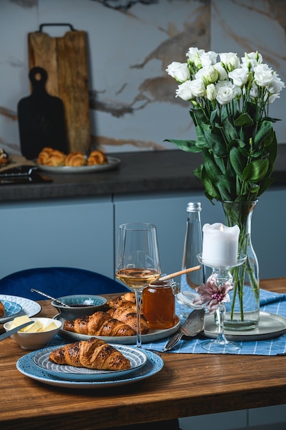 Croissants with butter and wine on a wooden table.