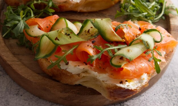 Croissants with cheese cream, red fish and cucumber on a wooden stand served for breakfast or lunch