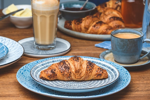 Croissant con una tazza di caffè su un tavolo di legno.