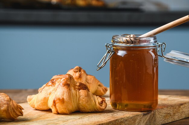 Croissants with honey on a wooden table.