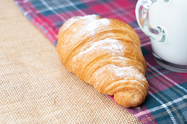 Croissants with icing and milk on table.