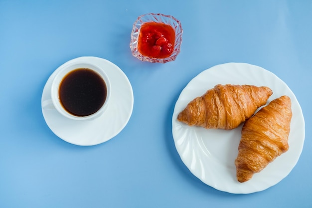 Croissants with jam and morning coffee flat lay Isolated on blue background