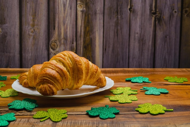 Croissants on wooden table with glittering clovers