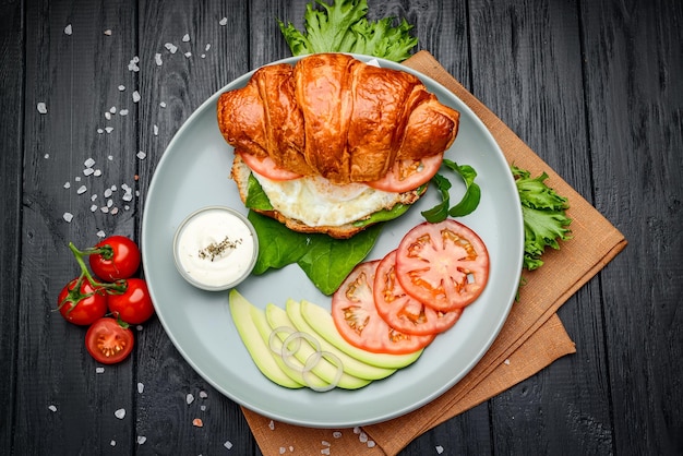 Croissantsandwich met avocado-rucola en gebakken ei als ontbijt Serveren in een café Foto voor het restaurantmenu