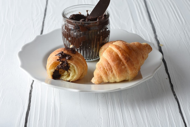 croissantVersgebakken croissants op een dienblad met een klein potje jam als ontbijt