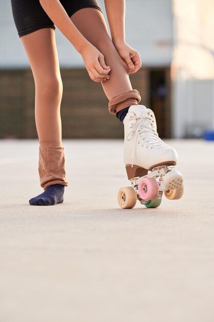 Foto ritaglia una ragazza anonima in quad che fissa i leggings sul percorso mentre si prepara per l'allenamento in una giornata estiva sulla strada della città