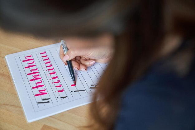 Crop anonymous lady doing brush lettering during lesson