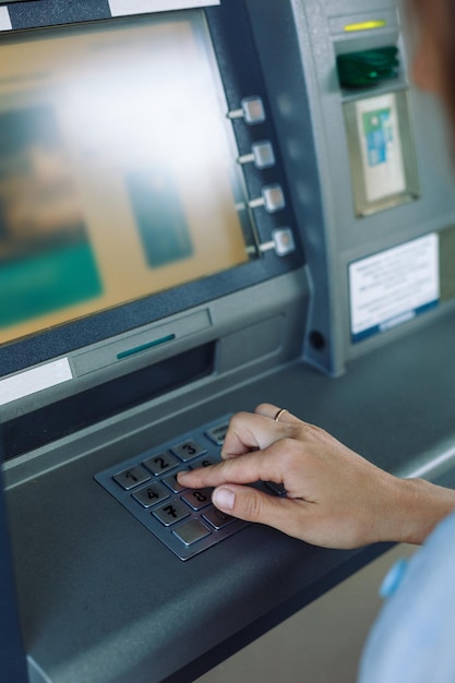 Crop anonymous woman pushing buttons on ATM committing financial operations