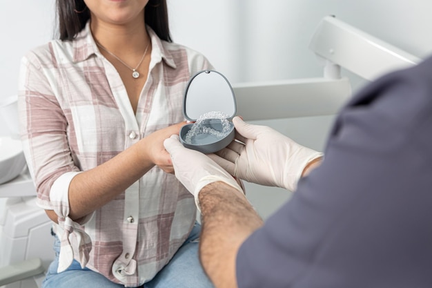 Crop anonymous woman taking aligners box from dentist