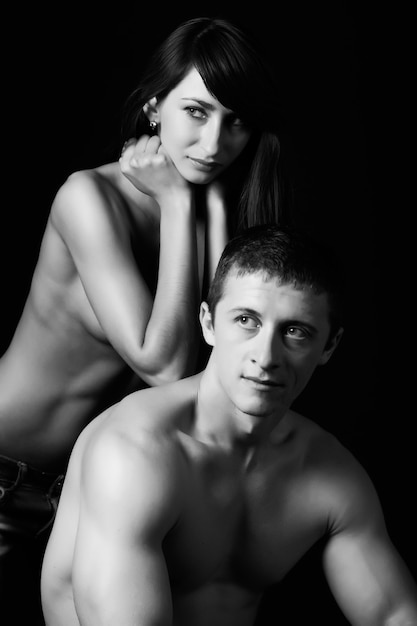 Crop of athletic young man with naked torso hugging charming girlfriend.