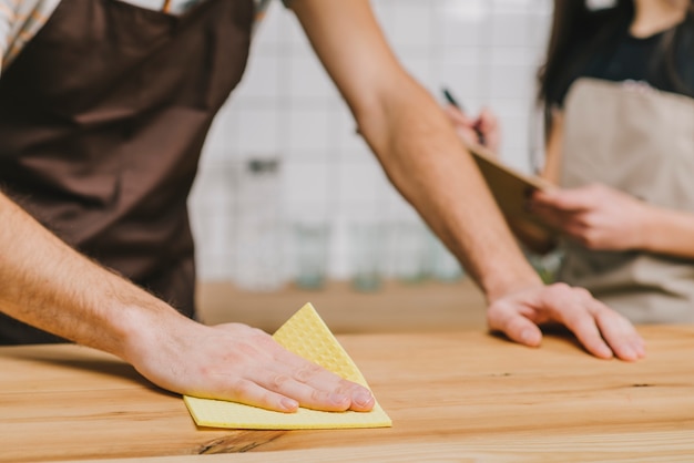 Crop barista cleaning counter