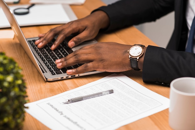 Crop black businessman typing in office