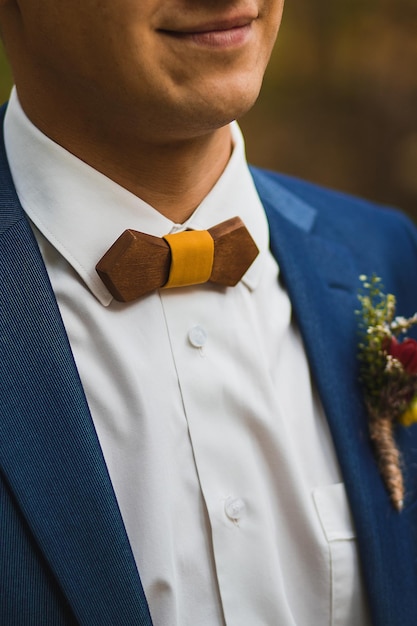 Crop caring wife straightening trendy wooden bow tie with\
yellow fabric knot to husband