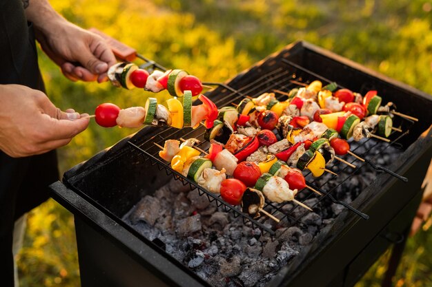 Crop chef cooking chicken and vegetable skewers