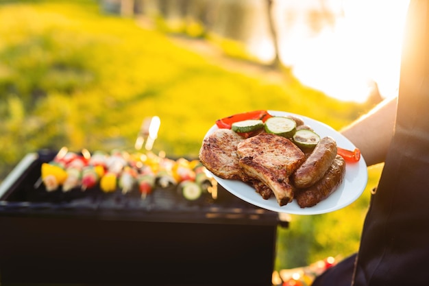 Crop chef with plate of grilled meat and vegetables