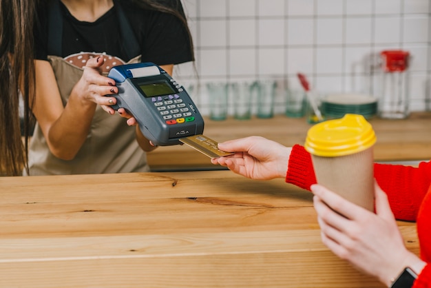 Foto ritaglia il cliente pagando per bere nella caffetteria