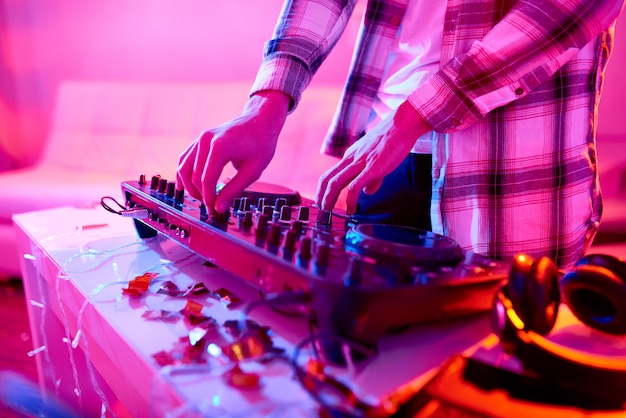 Crop DJ playing music on mixer