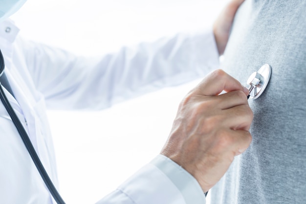 Crop doctor examining chest of patient