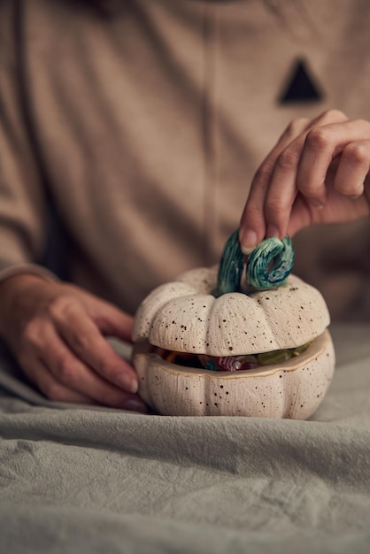 Crop female closing pumpkin with candies