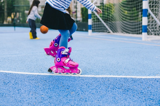 Photo crop girl riding roller skates on sports ground