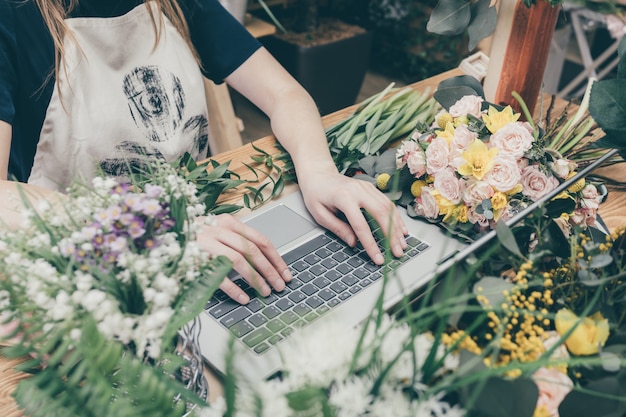 Crop girl using laptop in floral shop