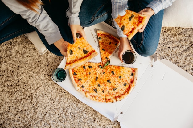 Photo crop girls having pizza on floor