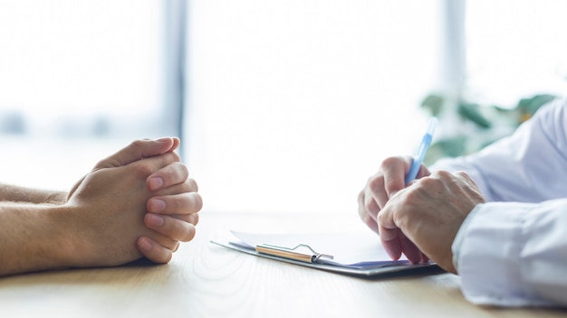 Foto ritaglia le mani di medico e paziente sulla scrivania