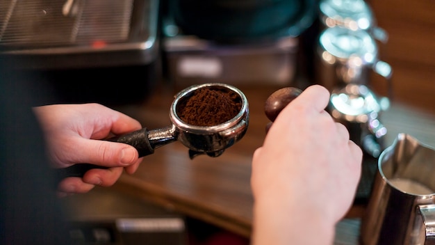 Ritaglia le mani tenendo il portafiltro con caffè fresco