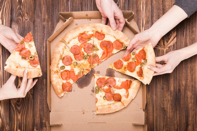 Crop hands holding slices of pizza