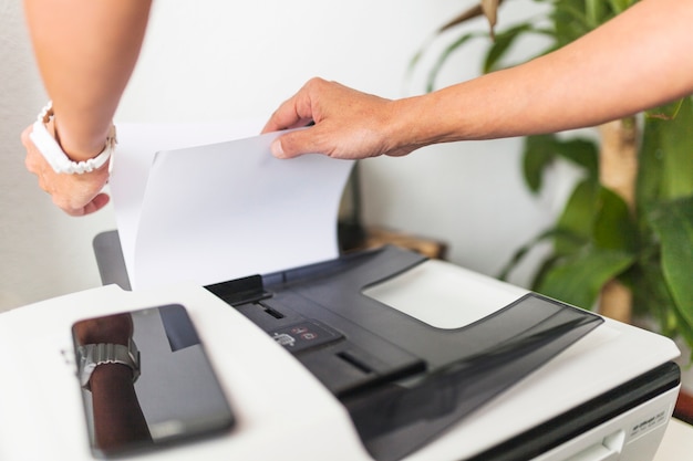 Crop hands touching paper in printer