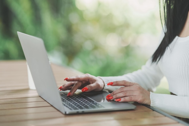 Crop image of asian freelance woman smile typing on keyboard and working on laptop on wooden table at home Entrepreneur woman working for her business at the cafe Business work at anywhere concept